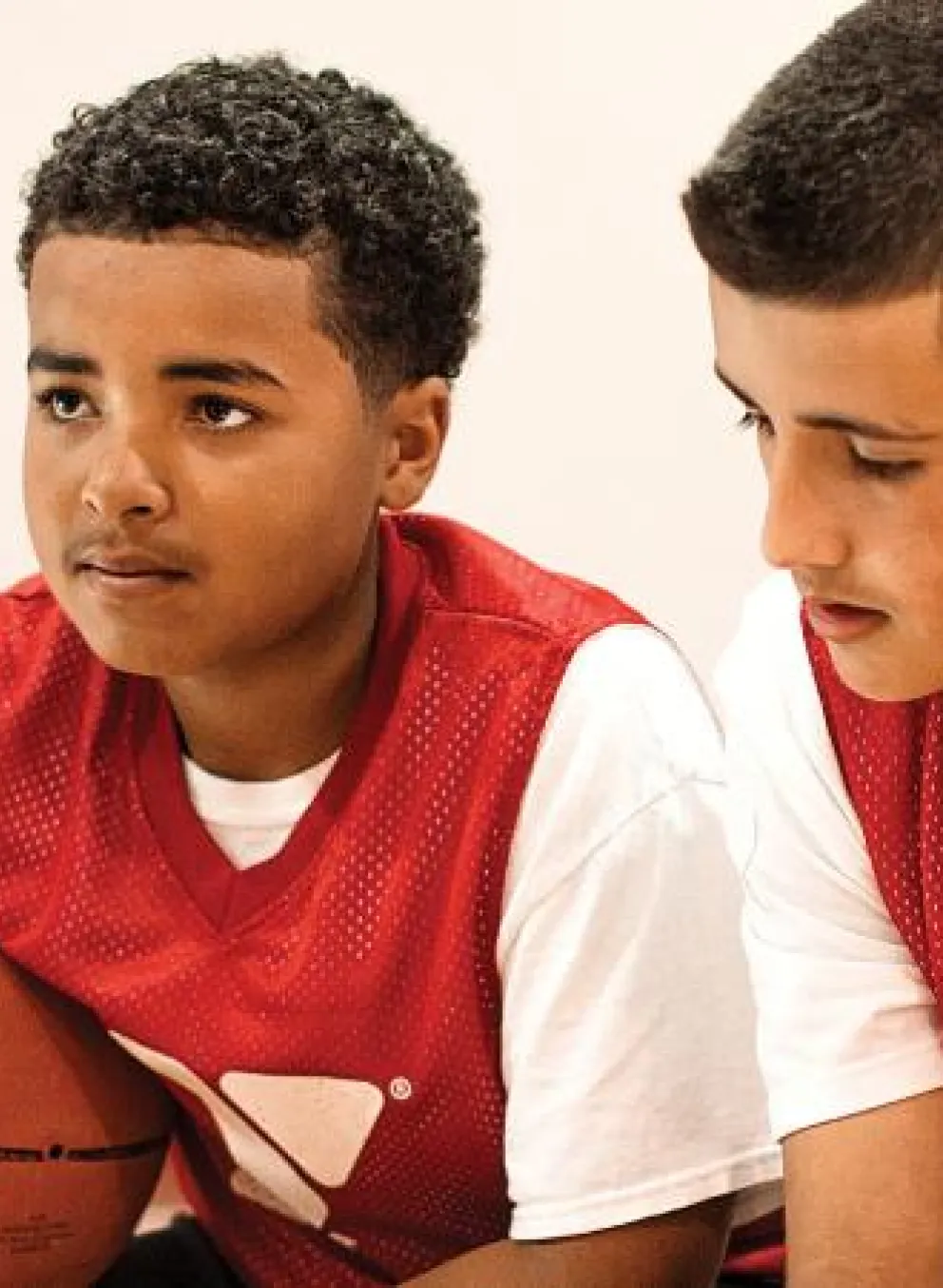 A coach instructing 3 youths in basketball.