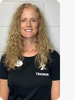 Female personal trainer wearing a black YMCA Trainer shirt in front of a gray wall.