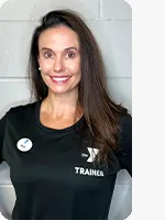 Female personal trainer wearing a black YMCA Trainer shirt in front of a gray wall.