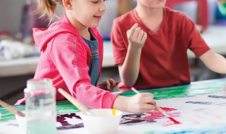 Two children painting on a canvas.