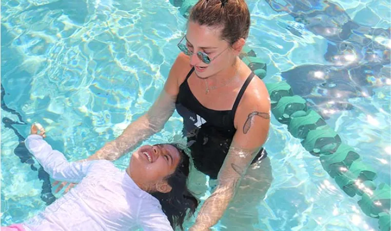 Instructor teaches child to float in pool at the Y.