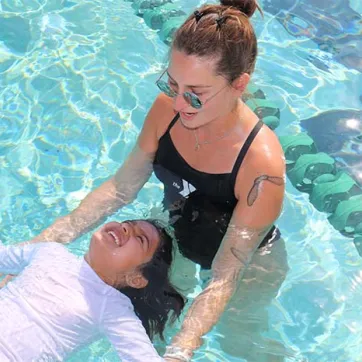 Instructor teaches child to float in pool at the Y.