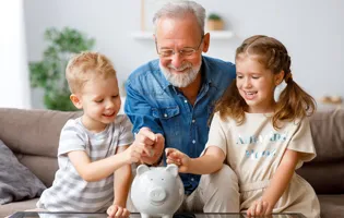 Grandpa with two kids adding money to piggy bank.